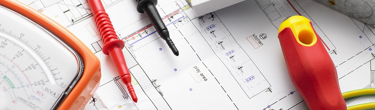 A multimeter and screwdriver on electrical plans