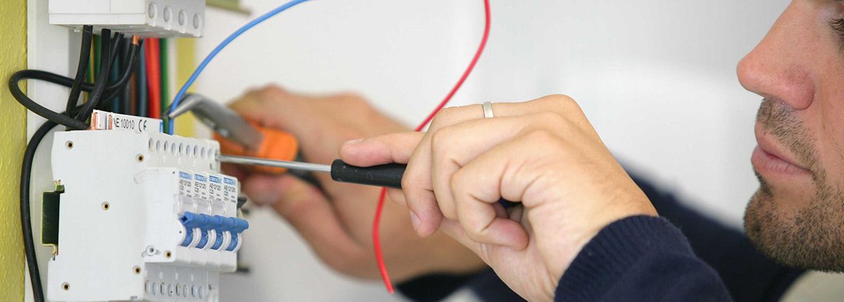 An electrician working on a breaker panel