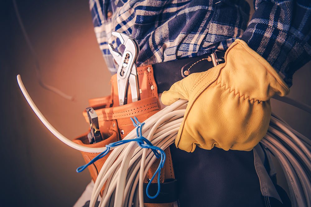 An electrician's tool belt, gloves and coiled wire