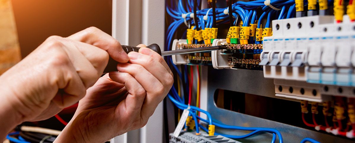 Hands with a screwdriver at a breaker panel